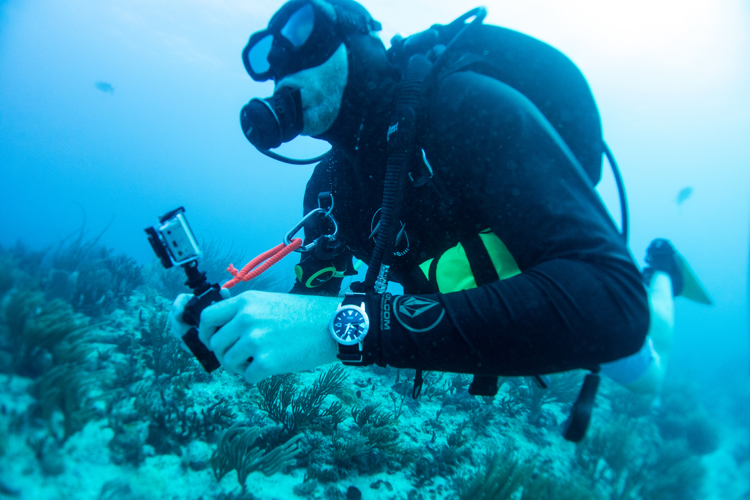 A scuba diver using separate underwater camera and wrist equipment
